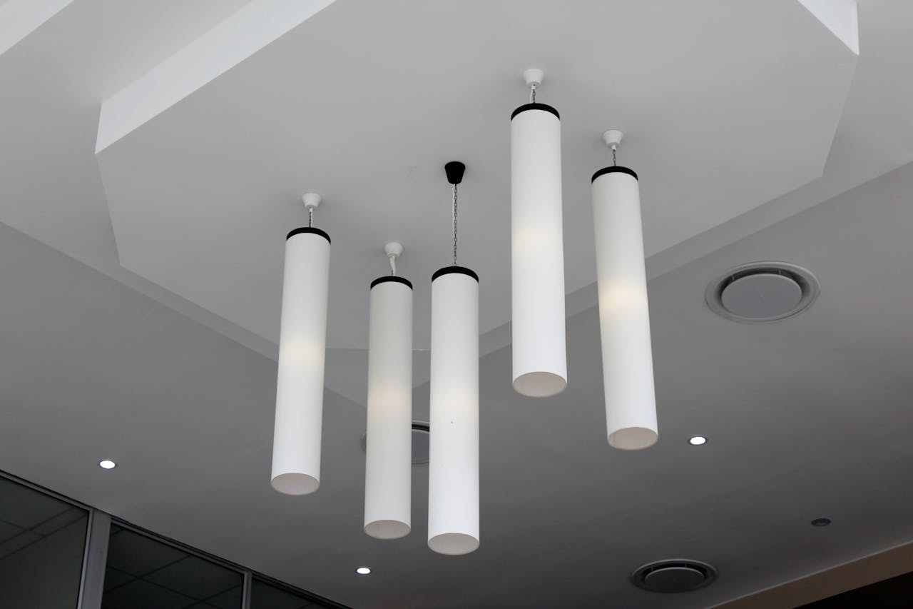 Minimalist modern interior with cylindrical hanging lights on a white ceiling.