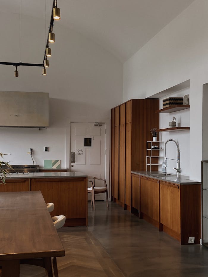 A modern kitchen with minimalist design featuring wooden cabinetry and contemporary lighting.